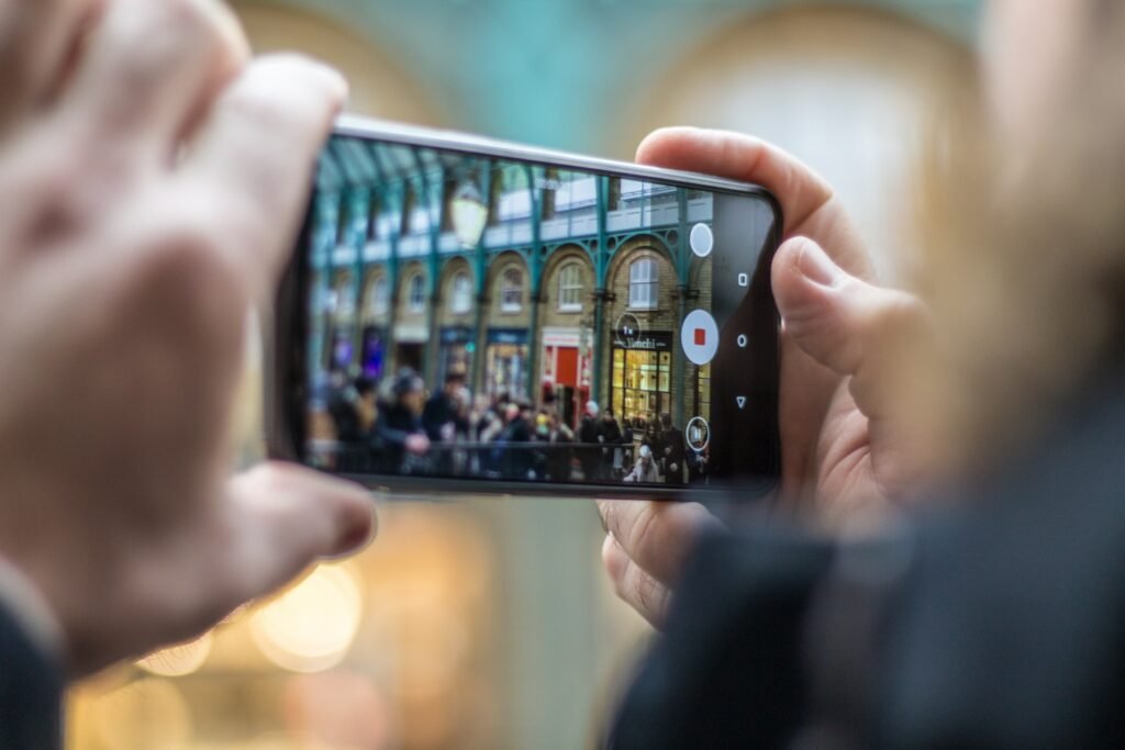 homem segurando um celular na horizontal enquanto tira foto do covent garden em londres, inglaterra