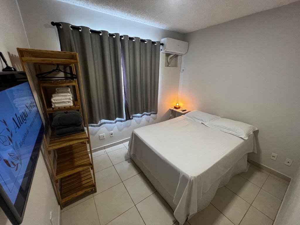 Quarto do Apartamento 4 andar. Uma cama de casal do lado direito, de frente um armário e uma televisão. No fundo uma janela e um ar-condicionado.