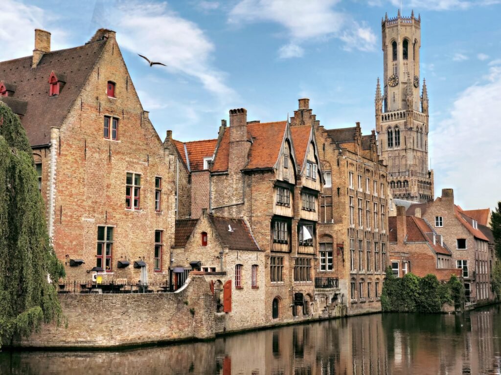 cidade medieval com construções em pedra na beira do canal com o Campanário de Bruges