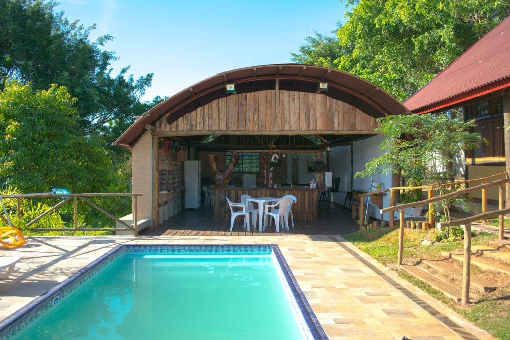 Imagem do Chalé Dom Quixote, para ilustrar o post sobre pousadas em Águas de São Pedro. Podemos ver uma piscina de azulejo e um rancho com churrasqueiras, mesas e um bar. 