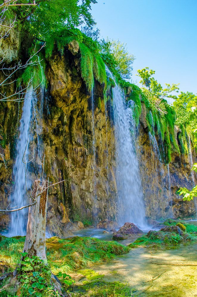 Uma cachoeira no Parque Nacional dos Lagos de Plitvice em um dia de céu azul.
