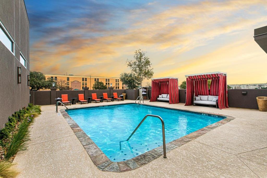 Piscina descoberta do DoubleTree by Hilton San Antonio Northwest - La Cantera com espreguiçadeiras e dois sofás com bangalôs nos arredores da piscina
