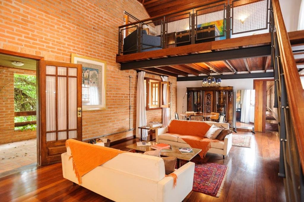 Recepção da pousada Locanda Buona Fortuna, com sofás e uma mesa de centro. No canto direito uma escada com visão para outro espaço de lazer e descanso.