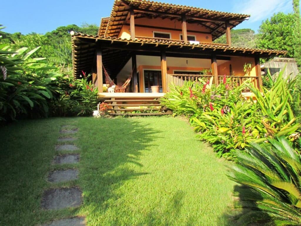 Frente da Casa Praia de Santiago durante o dia com jardim a frente e ao fundo a propriedade. 