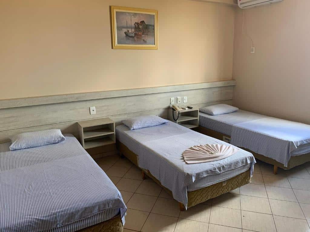 Quarto do Hotel Central. Três camas de solteiro do lado esquerdo, de cada lado duas prateleiras.