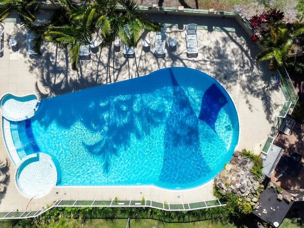 Vista de cima da piscina do Hotel & Pousada Sonho Meu com cadeiras de tomar sol ao redor e árvores.
