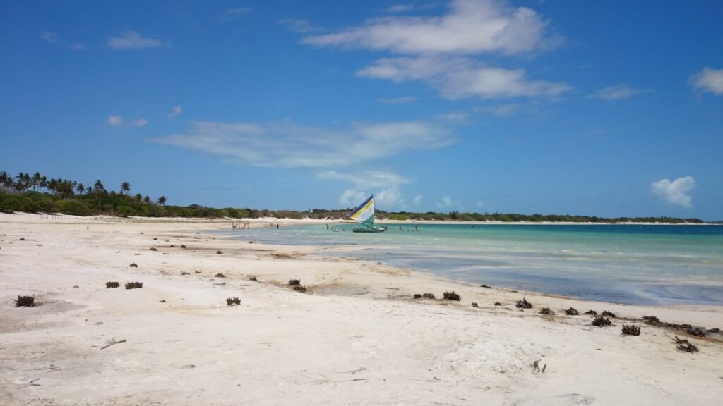 Barco no mar de Jericoacoara com areias brancas em volta da praia.