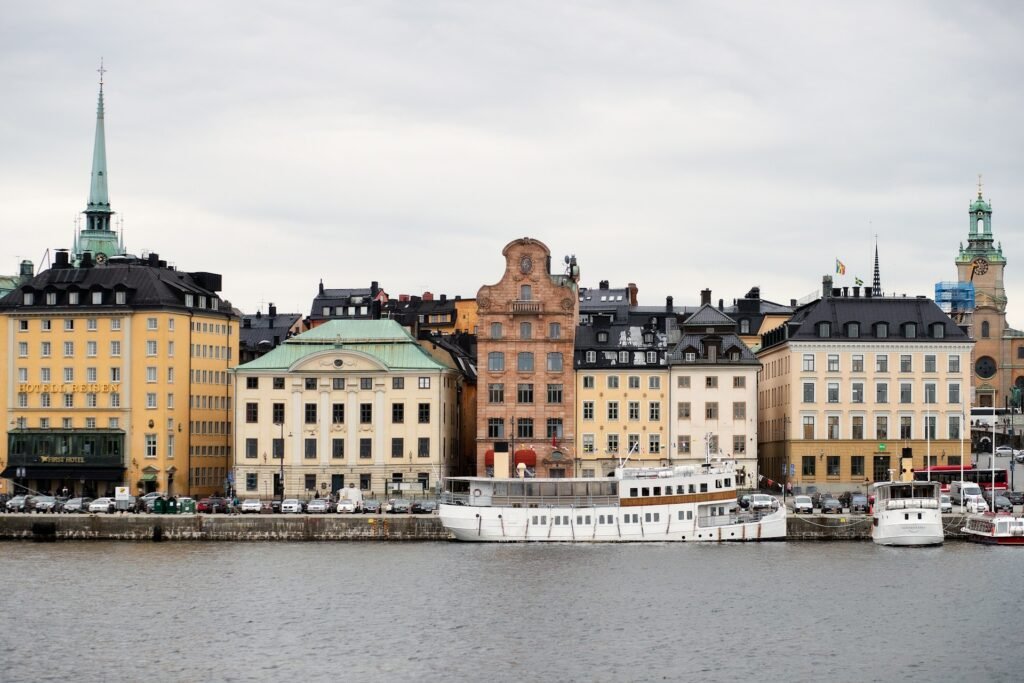 Vista da orla de edifícios históricos e barcos atracados em Estocolmo, sob um céu nublado. Esse é um dos destinos indicados no guia de mochilão pela Europa.