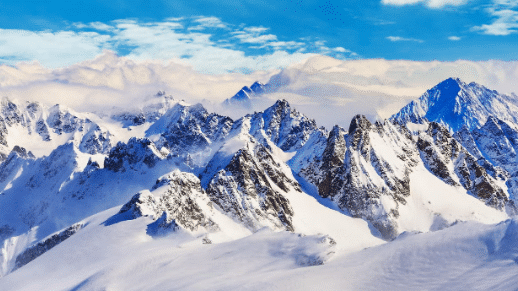 Picos de montanhas do Monte Titlis cobertos de neve sob um céu azul claro com nuvens dispersas ao fundo. Representa passeios na Suíça.
