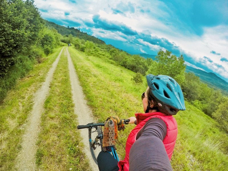 mulher andando de bicicleta numa estrada gramada em Groznjan