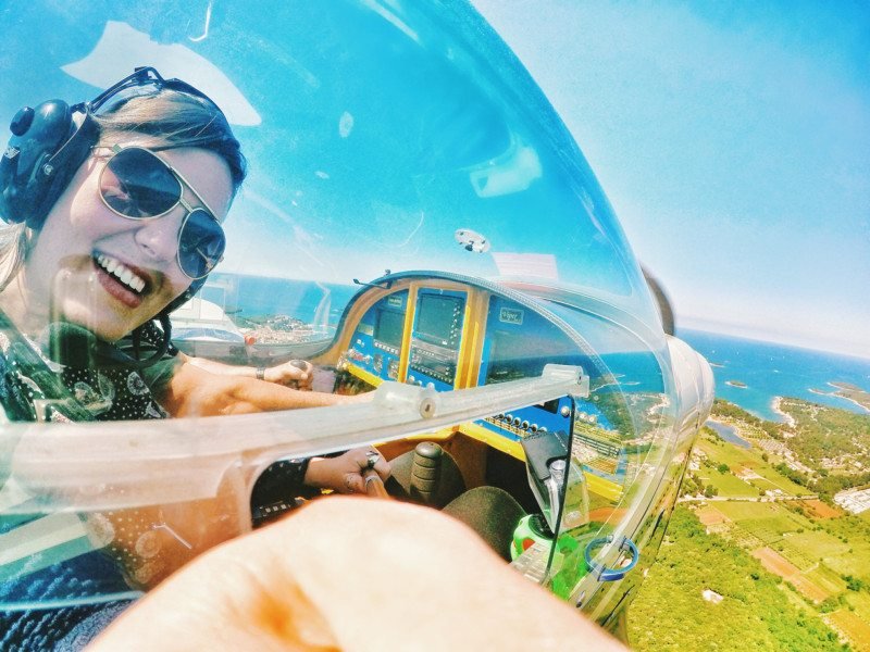 mulher tirando foto de si mesma dentro de um avião sobrevoando a cidade de Vrsar, na Ístria