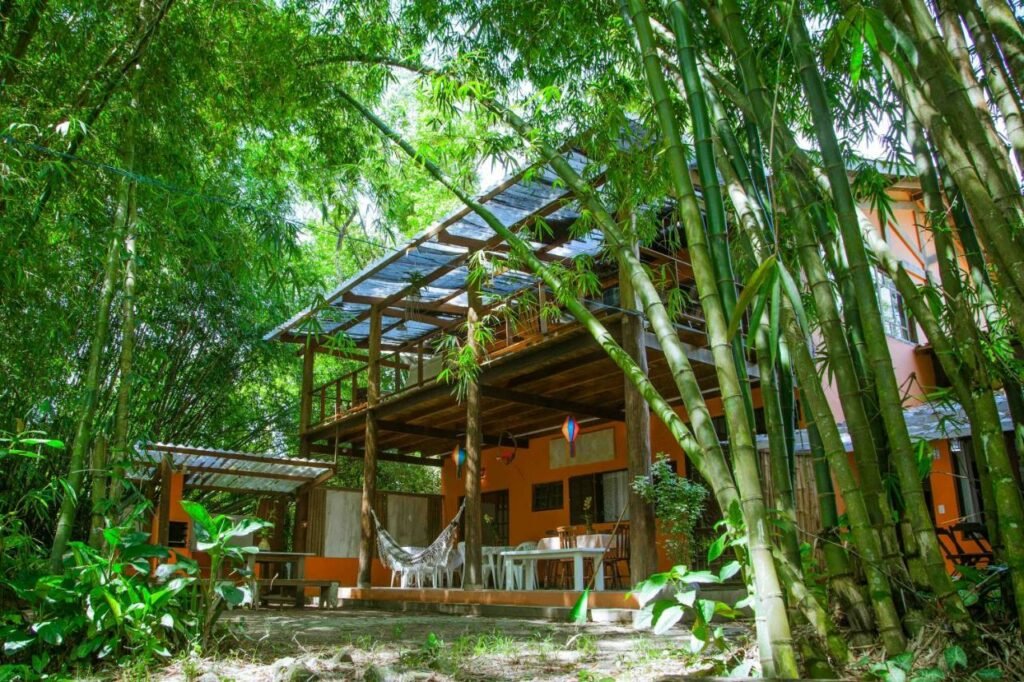 Vista de fora da Portal do Sabiá Maresias. Ela tem dois andares e é cercada por árvores e matos.