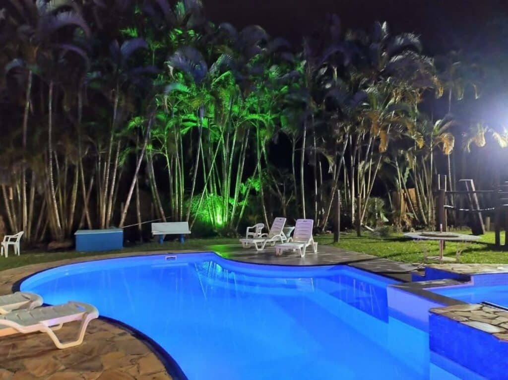 Piscina em área aberta da Pousada Estrela do Mar. Ela está cercada por espreguiçadeiras e árvores.