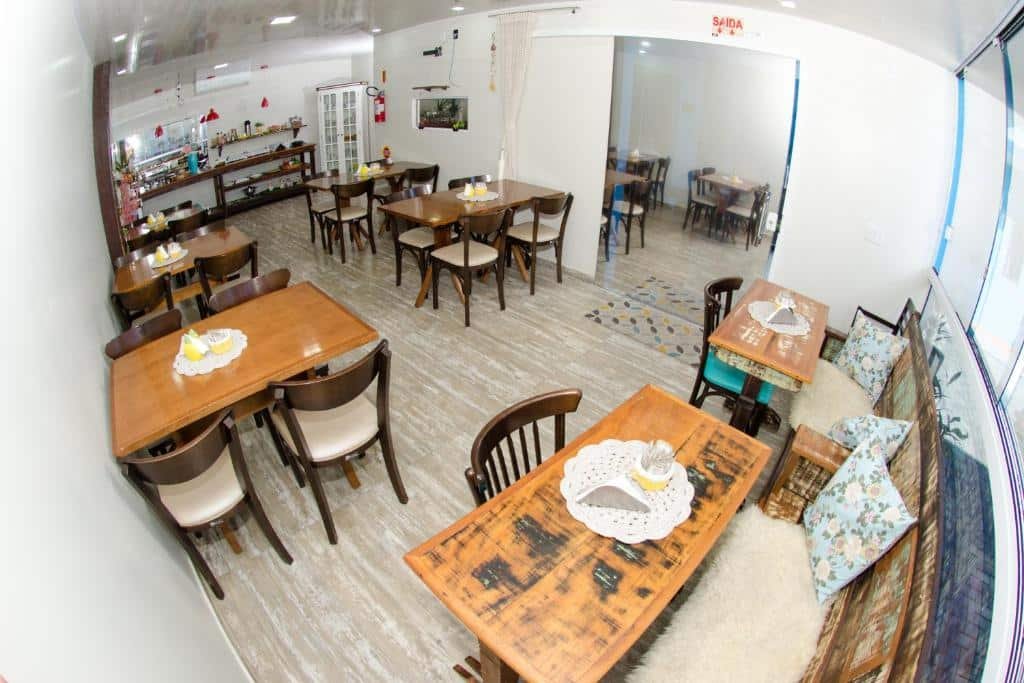 Lounge da Pousada Paraíso Tropical. Mesas e cadeiras decoradas, no fundo as mesas com o café da manhã.