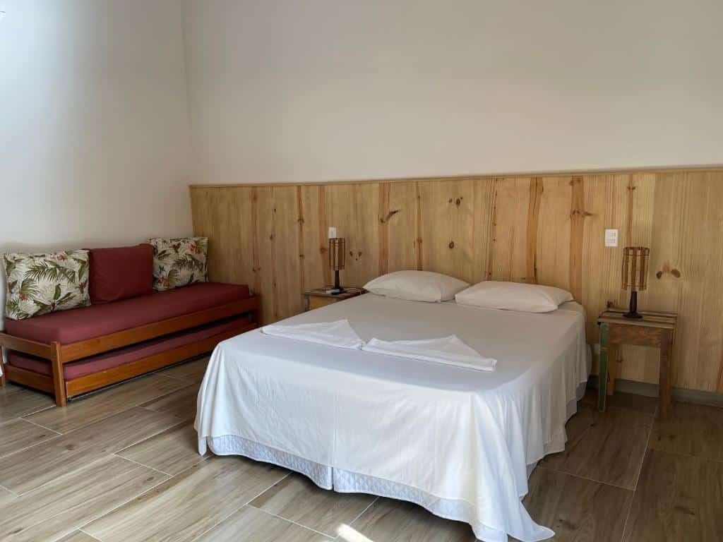 Quarto da Pousada Pé da Mata Maresias. Uma cama de casal está no meio, ao seu lado esquerdo um sofá cama. Dois abajures estão dos dois lados da cama. Foto para ilustrar post de pousadas pet friendly em Maresias.
