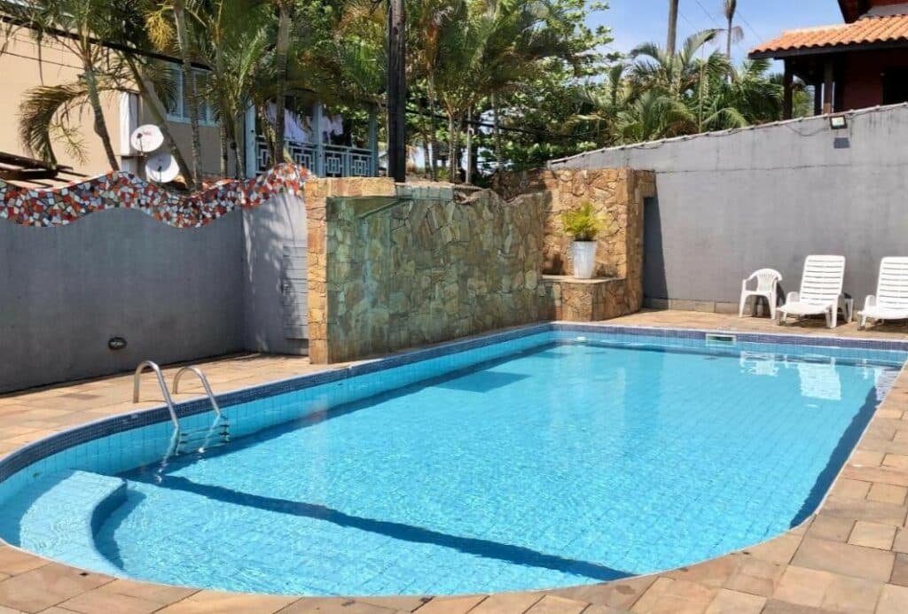 Piscina da Pousada Raio de Sol Maresias. Ela está em uma área aberta e perto de algumas cadeiras.
