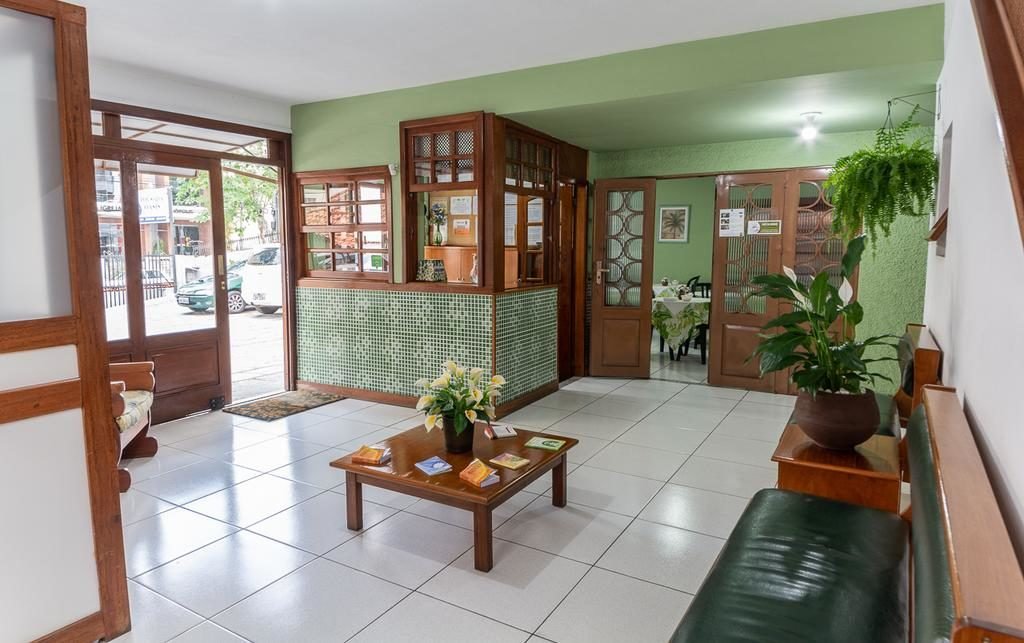 Recepção da pousada Oásis Teresópolis com paredes verdes e objetos em tons de marrom, ilustrando post pousadas em Teresópolis.