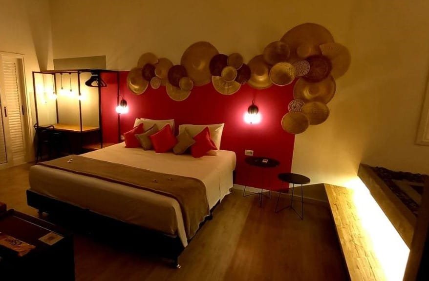 Quarto da Pousada Toca da Praia. Uma cama de casal está no meio, ao seu lado esquerdo uma mesa com várias luminárias. Do lado direito está uma banheira de hidromassagem. Essa é uma das melhores pousadas pet friendly em Maresias.