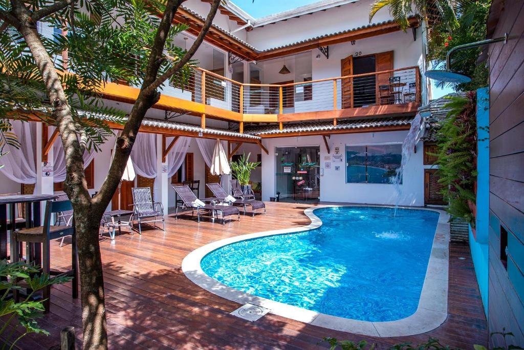 Piscina da Pousada Vila Barequeçaba em um deck com ducha. Algumas espreguiçadeiras e árvores estão ao redor. 