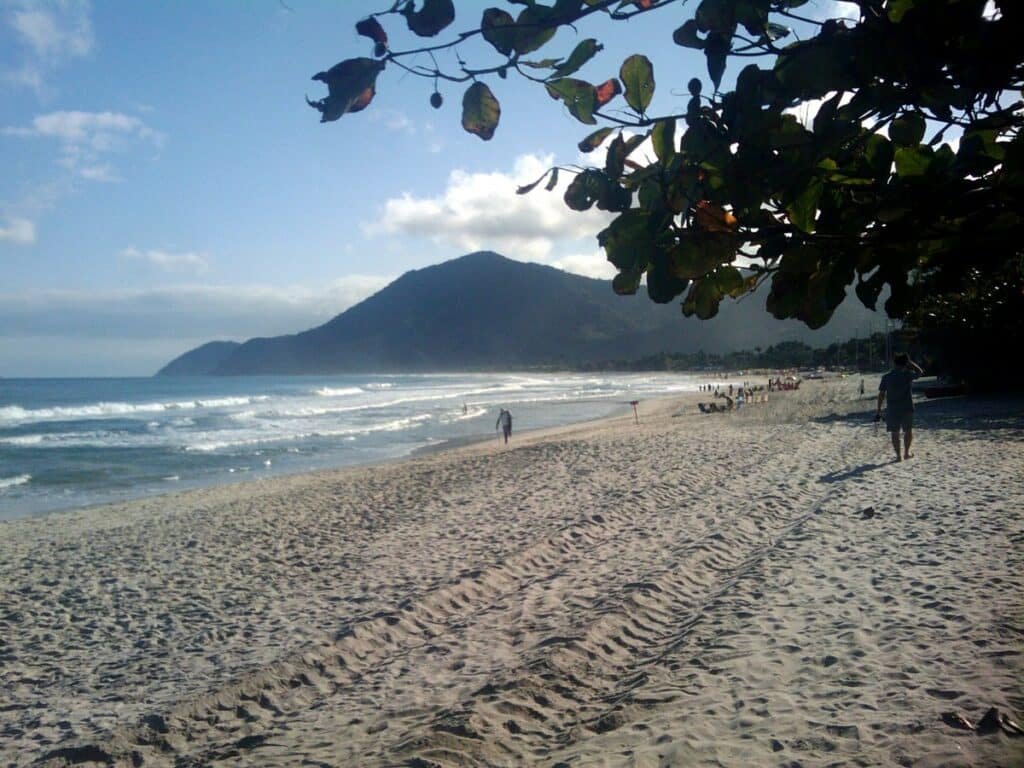 Faixa de areia e mar da praia de Maresias. Ao fundo é possível ver algumas pessoas sentadas e outras passeando. Foto para ilustrar o post de pousadas pet friendly em Maresias.