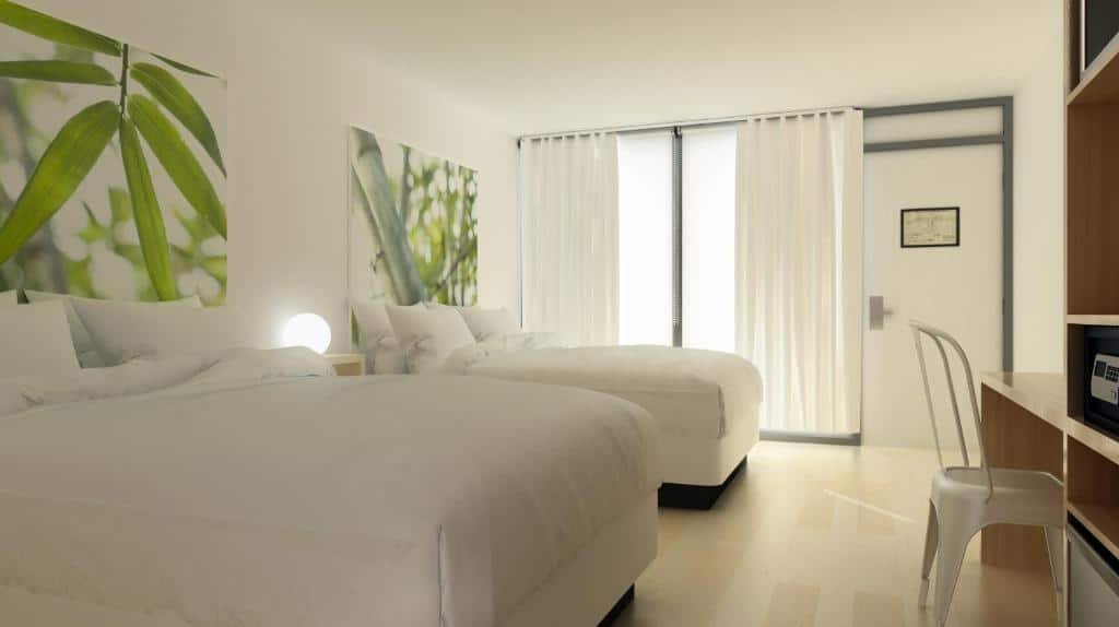 quarto do GreenPoint Hotel Kissimmee com duas camas, luminária e mesinha no meio delas e uma janela enorme de vidro com cortinas