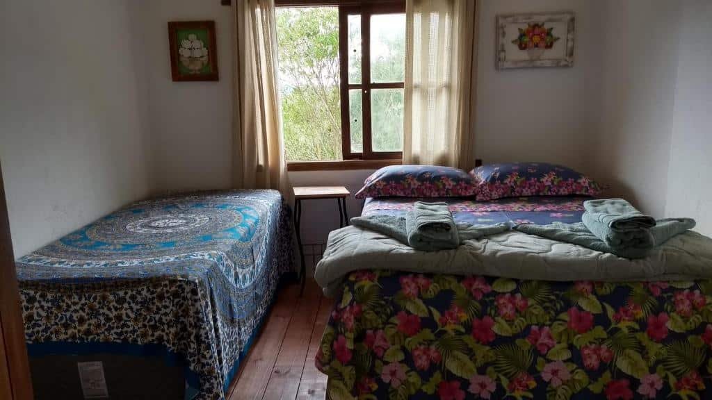 Quarto com cama de casal e uma cama de solteiro em Aqua Montis Pousada.