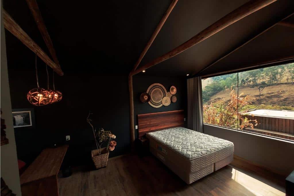 Quarto Bangalô Luxo entre lindas cachoeiras com cama, luminárias e uma ampla janela.