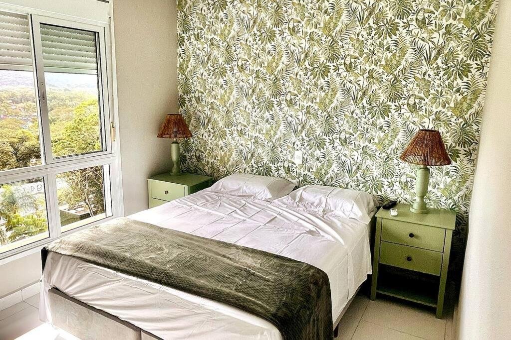 Quarto do Camburizinho 3 suítes aconchegante com cama de casal no centro do quarto com uma cômoda em cada lado da cama com luminária. Representa airbnb em São Sebastião.