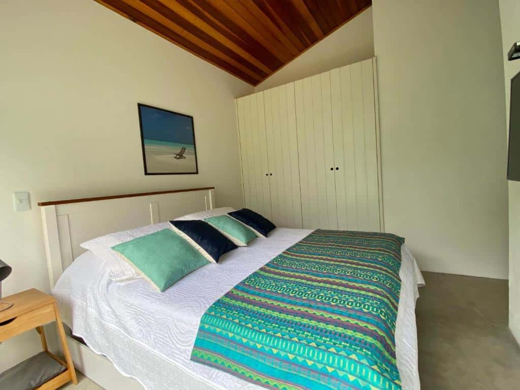 Quarto da Casa Amendoeiras – spa aquecido e wifi com cama de casal do lado esquerdo da imagem com uma cômoda do lado esquerdo da cama. Representa airbnb em São Sebastião.