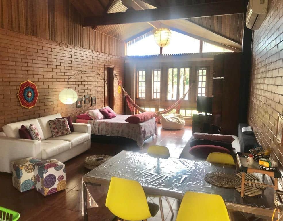 Vista do quarto amplo do EccO Capricornio  com cama, sofá e TV.