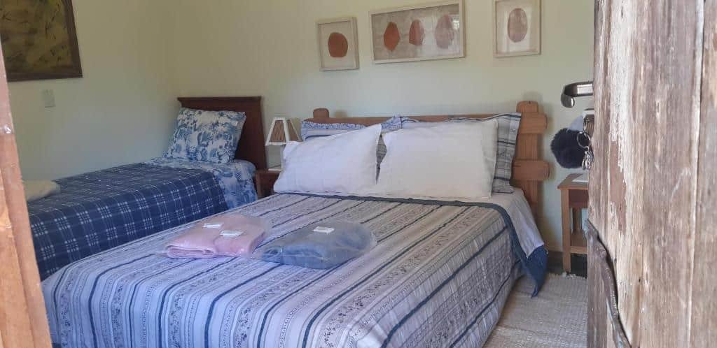 Vista do quarto Pousada Fazenda São Pedro com cama de casal e uma cama de solteiro.