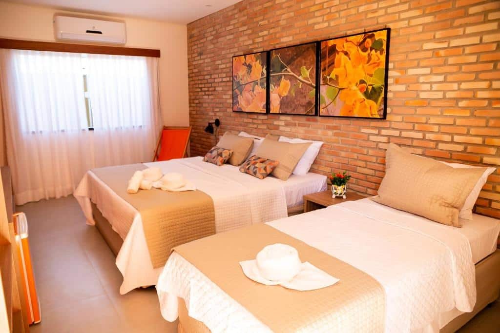 Quarto com cama de casal e uma de solteiro na Pousada das Flores.