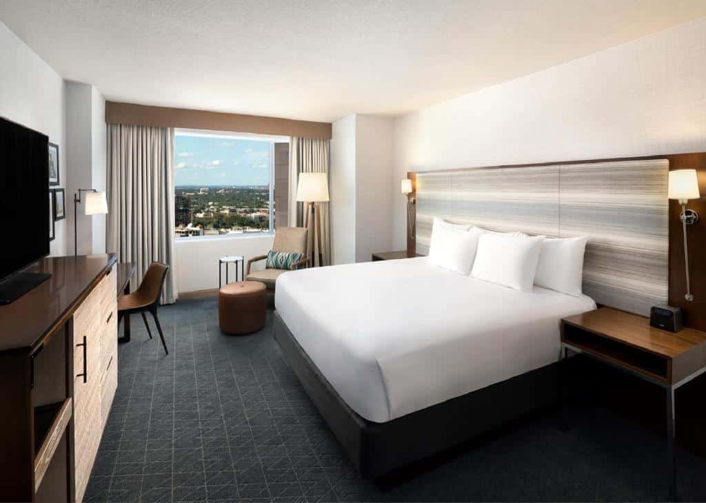 Quarto do Grand Hyatt San Antonio River Walk com uma cama de casal, uma janela com cortinas, uma mesa de escritório com uma cadeira, e um móvel com uma televisão em cima