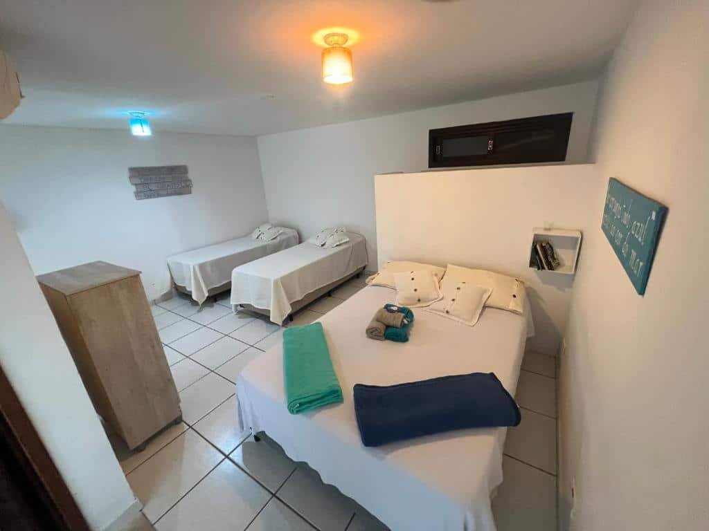Quarto do Loft com vista ao mar com cama de casal do lado direito da imagem e do lado esquerdo duas camas de solteiro. Representa airbnb em São Sebastião.