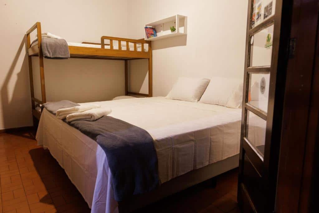 Quarto familiar do Natureza a 100m da Praia com cama de casal do lado direito da imagem a frente e do lado direito da cama de casal uma cama beliche. Representa airbnb em São Sebastião.