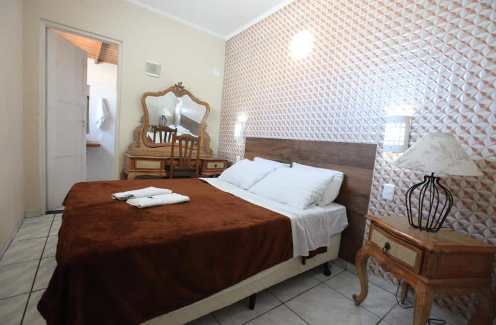 Quarto na Pousada dos Franceses. Uma cômoda no lado direito do lado da cama. Atrás da cama uma penteadeira, ao  lado da penteadeira a porta do banheiro.