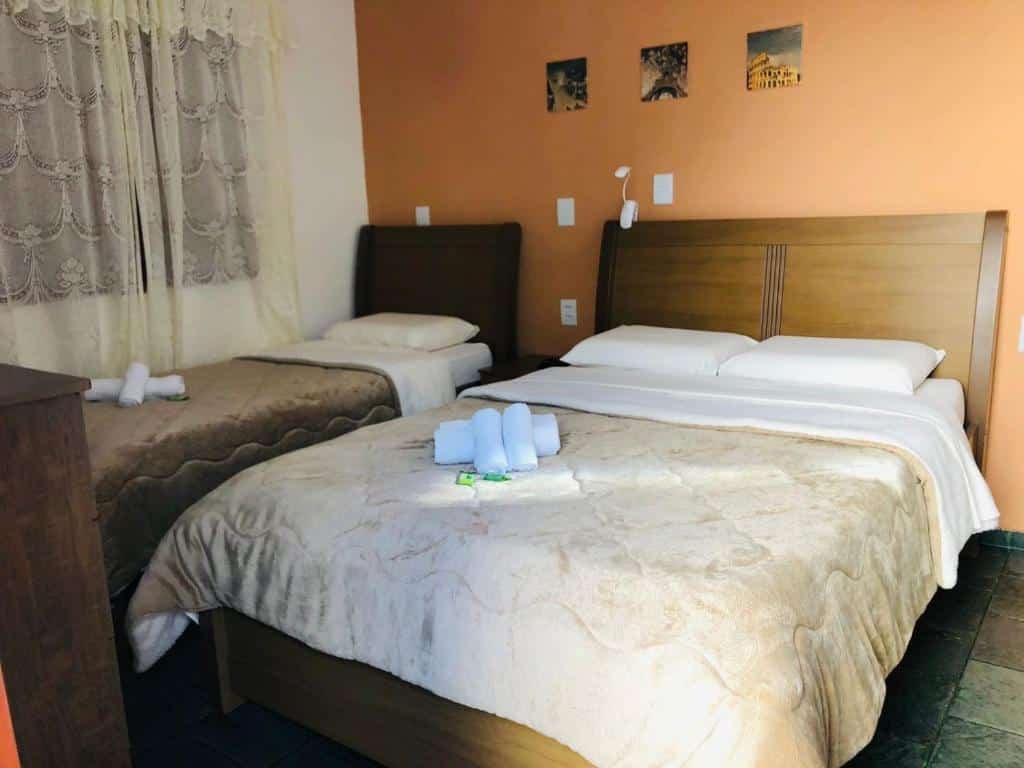 Quarto com cama de casal e uma de solteiro da Pousada Recanto das Flores .