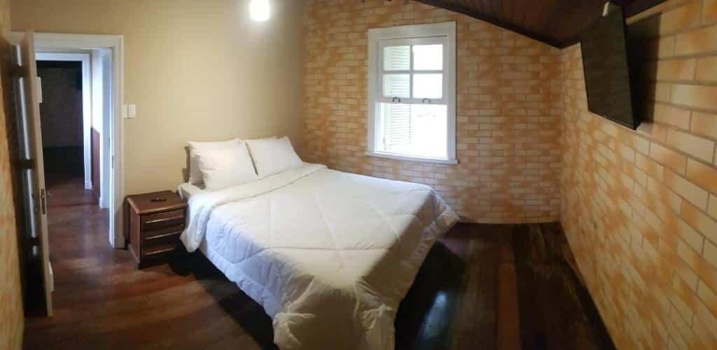 Quarto da pousada pé da tartaruga em Teresópolis com cama de casal, janela na cor branca e uma televisão na parede, ilustrando post pousadas em Teresópolis.