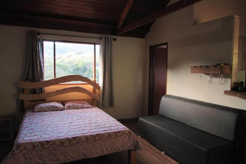 Quarto da Pousada Recanto do Ypê com cama, sofá e banheiro. 