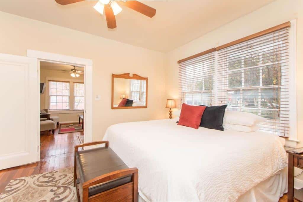 Quarto do THE MADISON - San Antonio Riverwalk - Downtown - Convention Center com uma cama de casal, duas janelas com persianas, um espelho, um ventilador de teto e um pequeno sofá com dois lugares