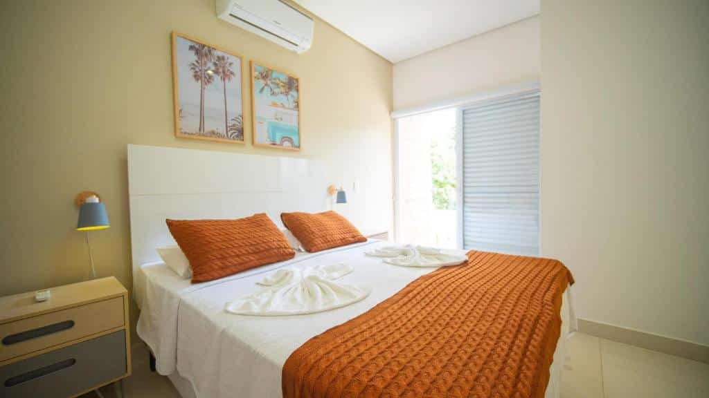 Quarto do Residencial Las Salinas. Uma cama de casal está no meio, ao lado de uma mesinha com duas gavetas e um abajur. Do outro lado, ao fundo, há uma janela. Esse é um dos airbnb em Maresias.
