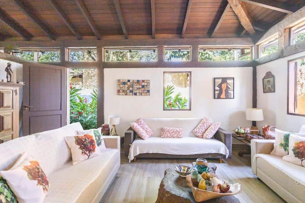 Sala de estar da Casa na Barra do Sahy com mesa ao centro do lado direito e esquerdo sofá e em frente outro sofá.