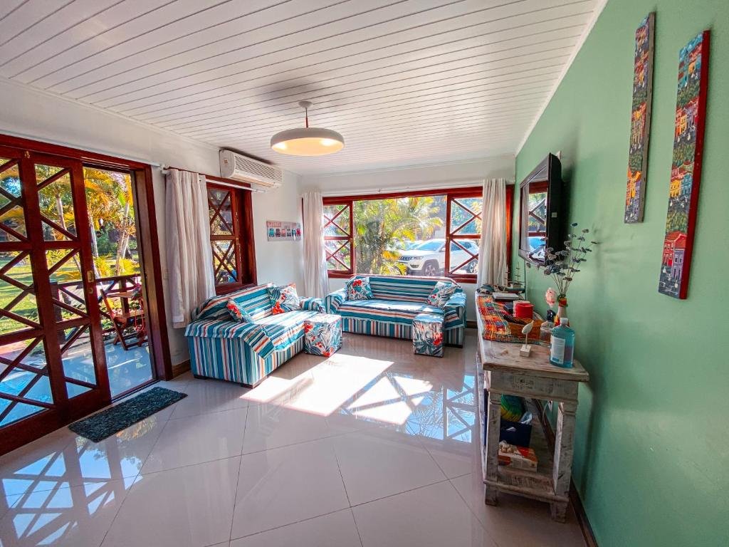 Sala de estar do Flat Completo e Decorado em Maresias com dois sofás ao fundo e a frente uma cômoda com TV presa na parede.